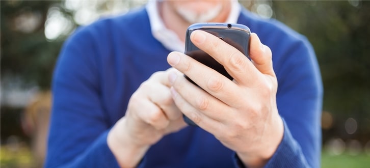 A man checking his phone after receiving a text alert from CenterWell Pharmacy about his upcoming order